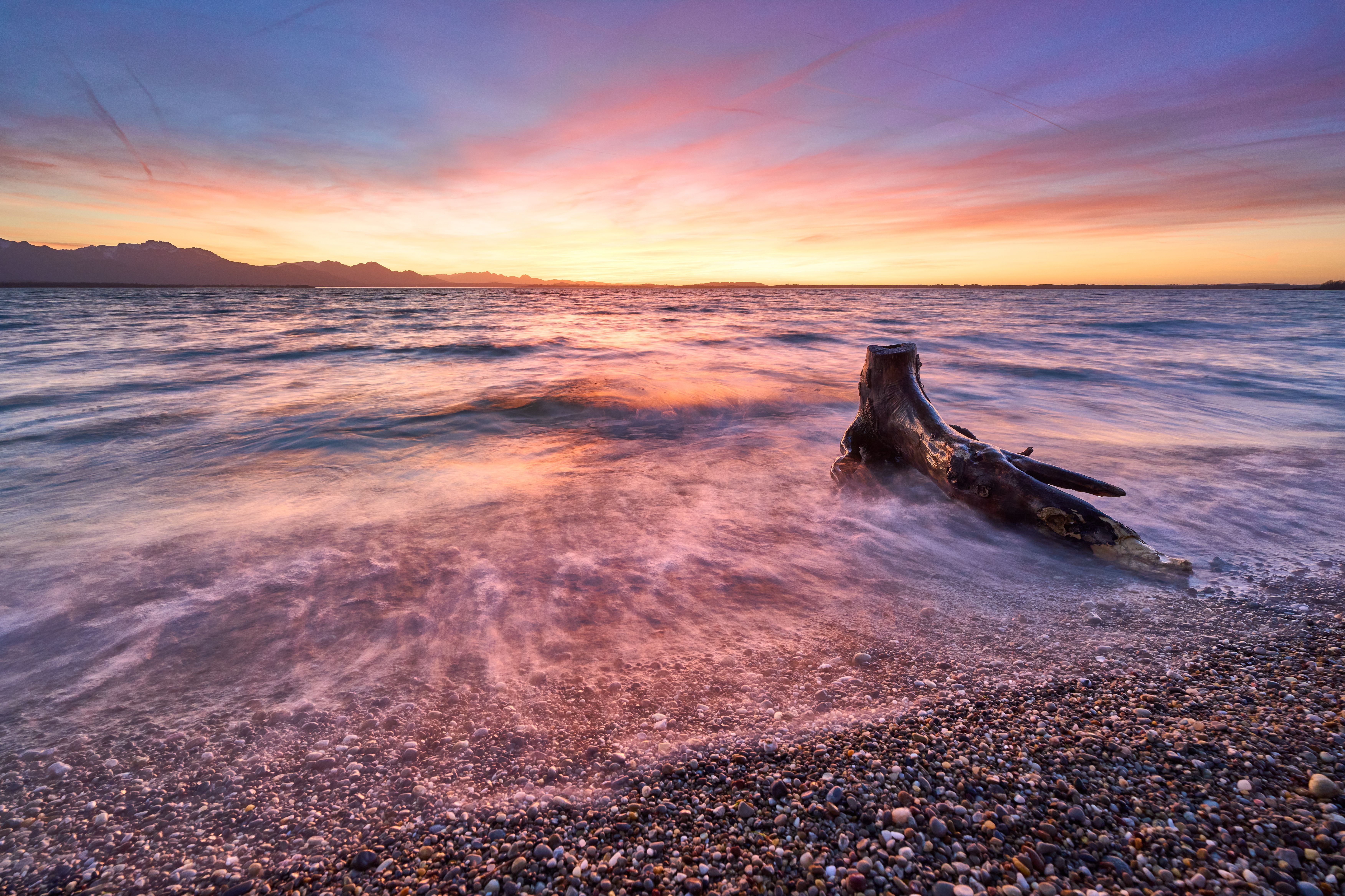 A sunset on the beach with a driftwood log · Free Stock Photo