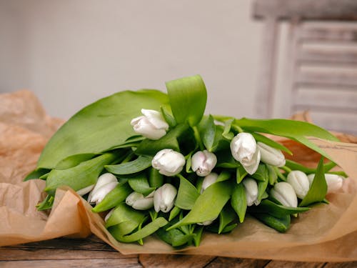 A bouquet of white tulips on a brown paper bag