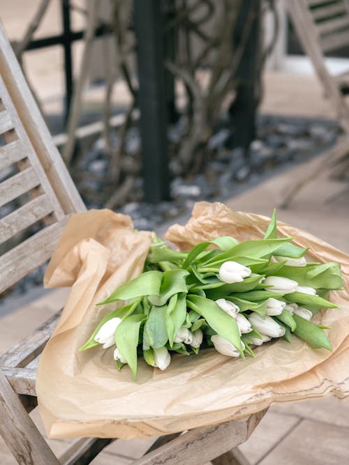 A bouquet of white tulips sitting on a chair