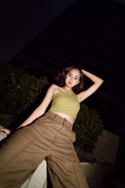 Low Angle Shot of a Young Woman in a Trendy Outfit Posing Outside at Night 