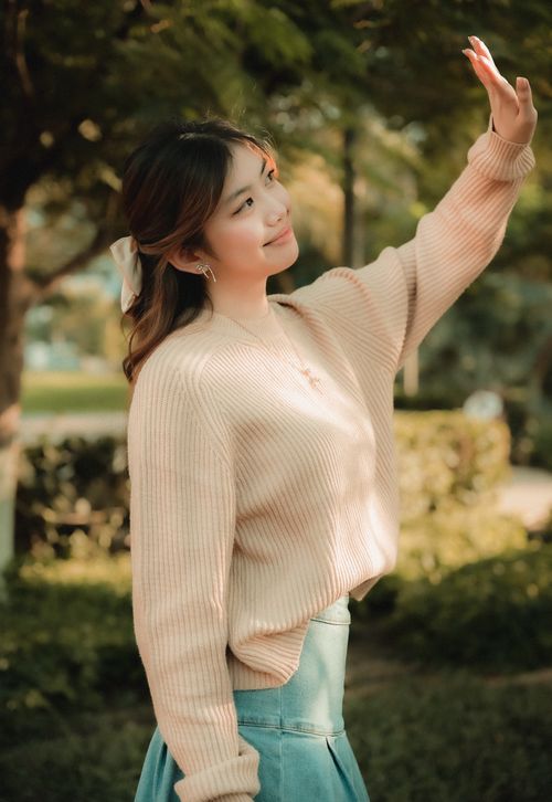 Free Portrait of a young woman in a sweater enjoying a sunny day outdoors. Stock Photo