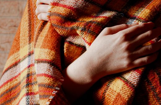 Woman wrapped in a blanket trying to warm up indoors