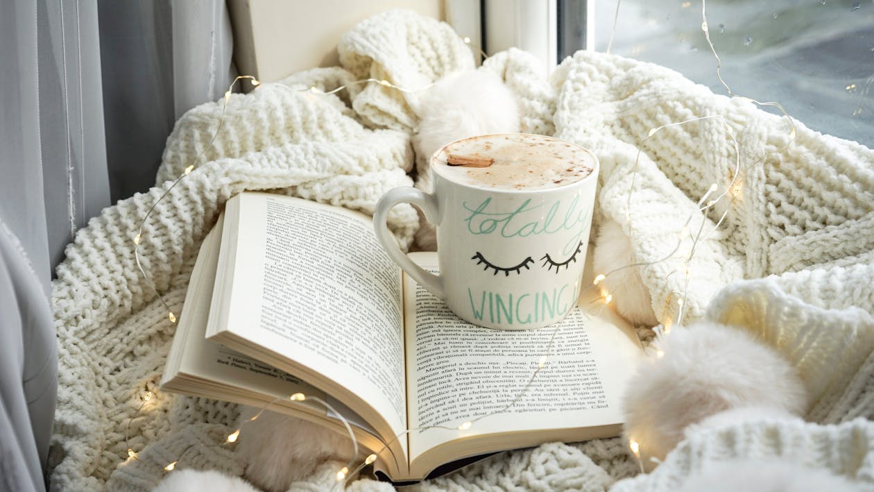 Free Coffee in Mug on Opened Book by Window Stock Photo
