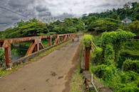 在印度尼西亚郁郁葱葱的卡布帕滕普尔瓦卡塔，两名摩托车手正骑过一座生锈的桥梁