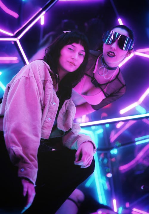 Two women in neon lights sitting on a couch