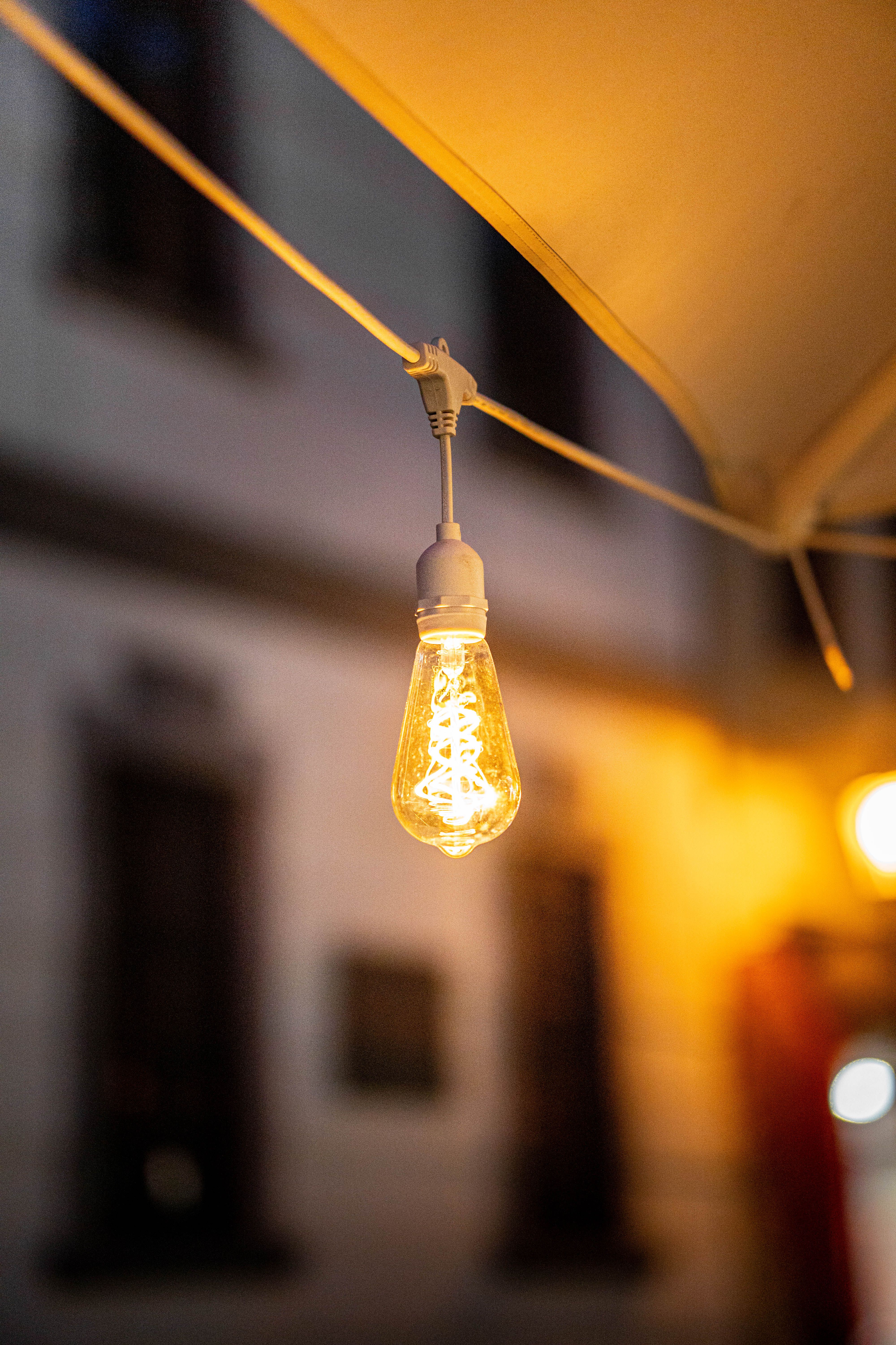 A glowing LED filament bulb elegantly hanging outdoors at night, creating a warm ambiance.