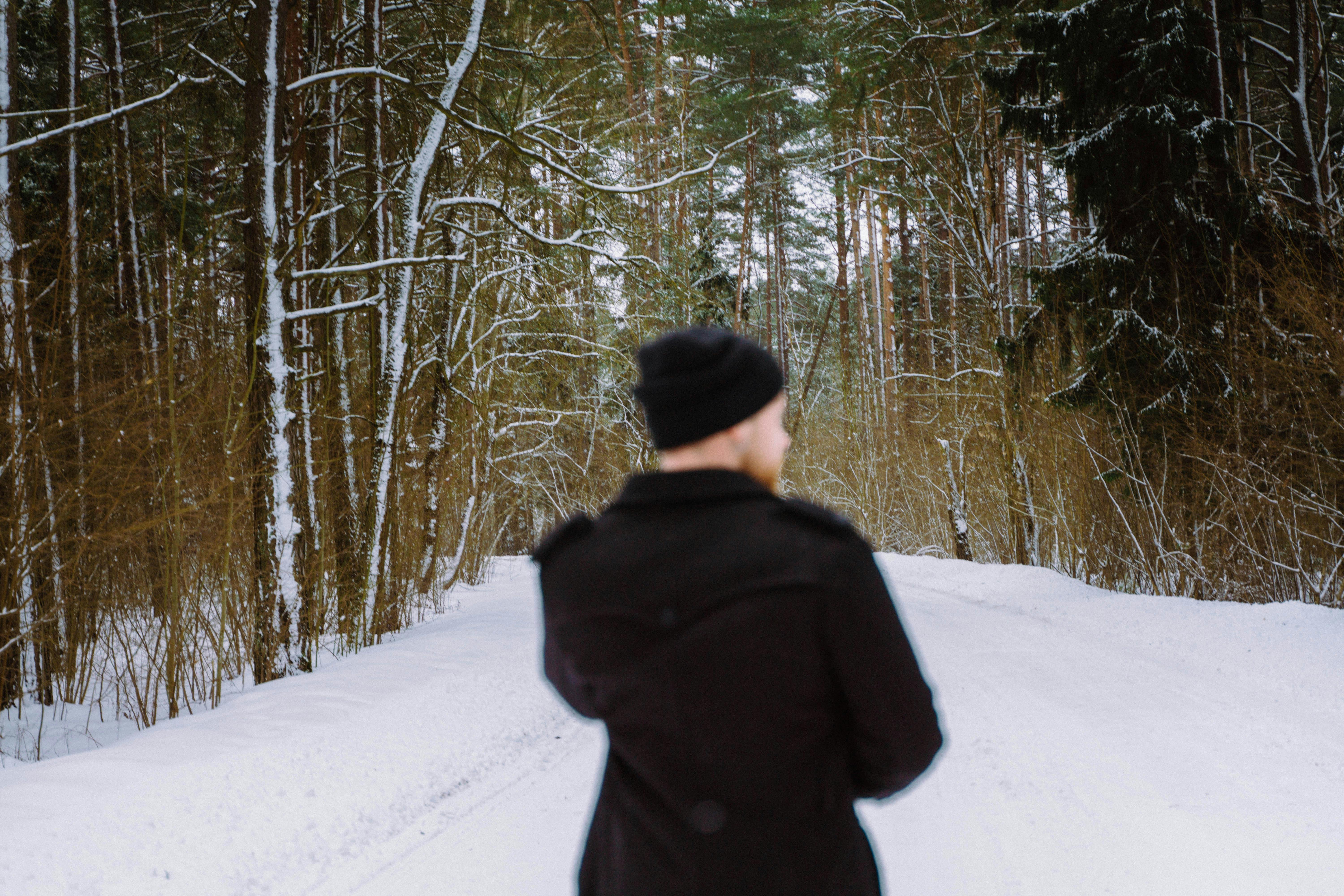 a young guy in a black coat went out into the winter woods to hang out