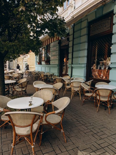 A delightful outdoor café with wicker chairs and tables on a cobblestone sidewalk, perfect for urban leisure.