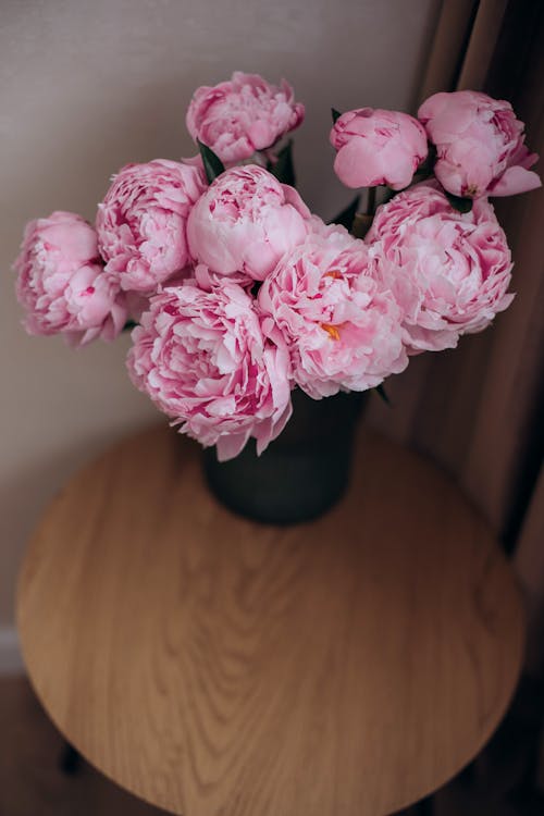 A vase of pink peonies on a table