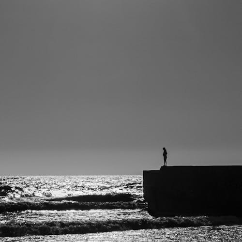 Free Woman Silhouette Standing on Pier on Sea Coast Stock Photo