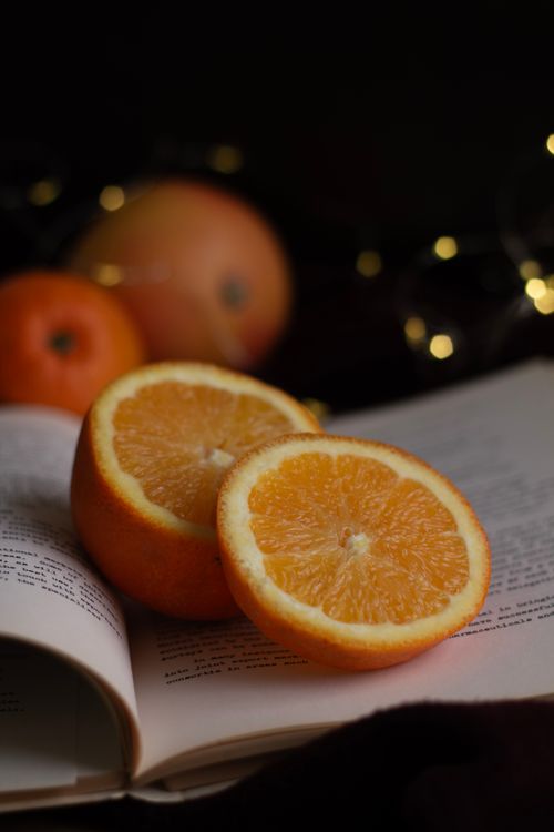 Free Sliced orange placed on an open book, creating a rustic and fresh ambiance. Stock Photo