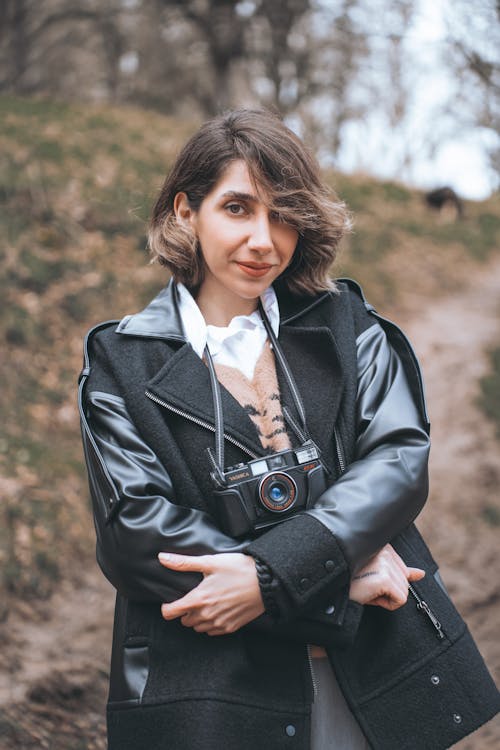 Young Woman with a Camera on a Strap Hanging on Her Neck Standing Outside 