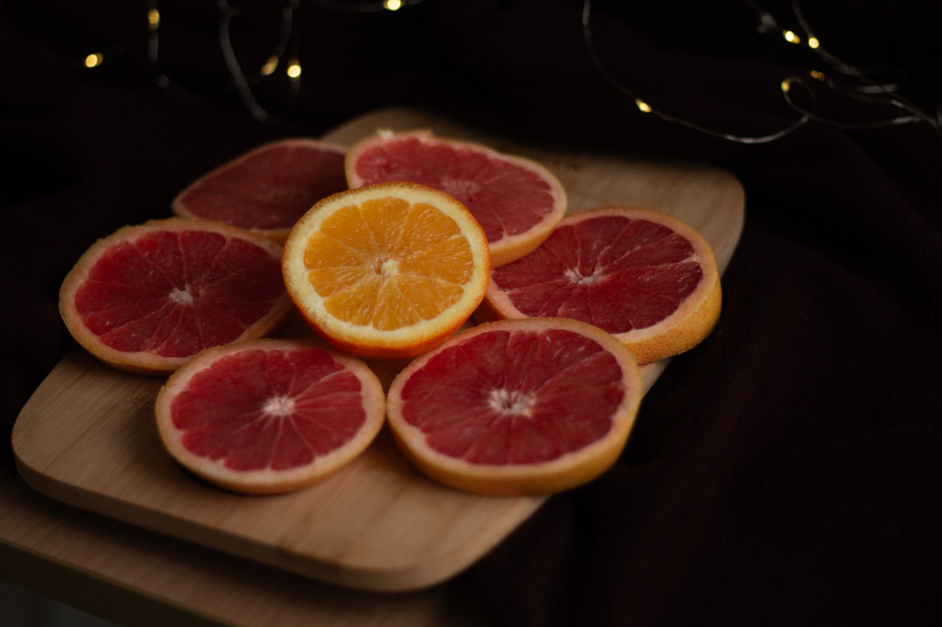 Close-up of fresh grapefruit and orange slices on a wooden cutting board.