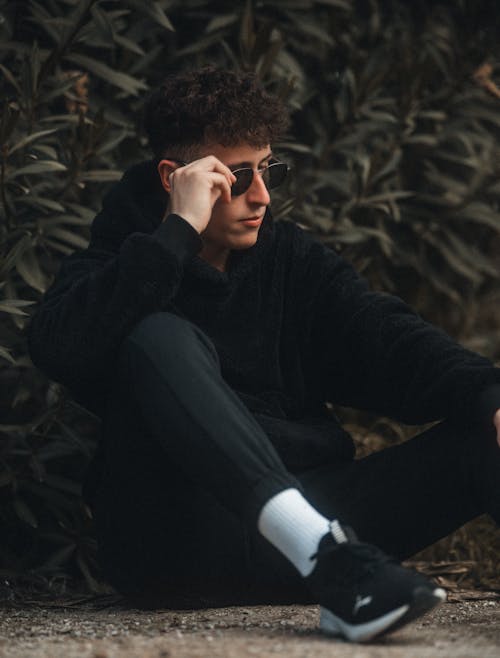 Man Sitting in Black Clothes and Sunglasses