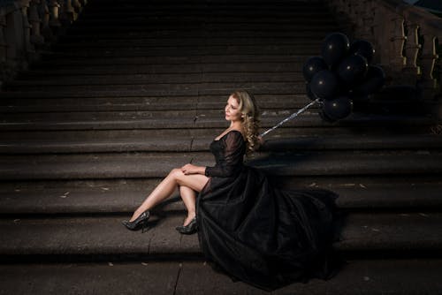Female Model Sitting on Dark Steps with a Bunch of Balloons in Hand