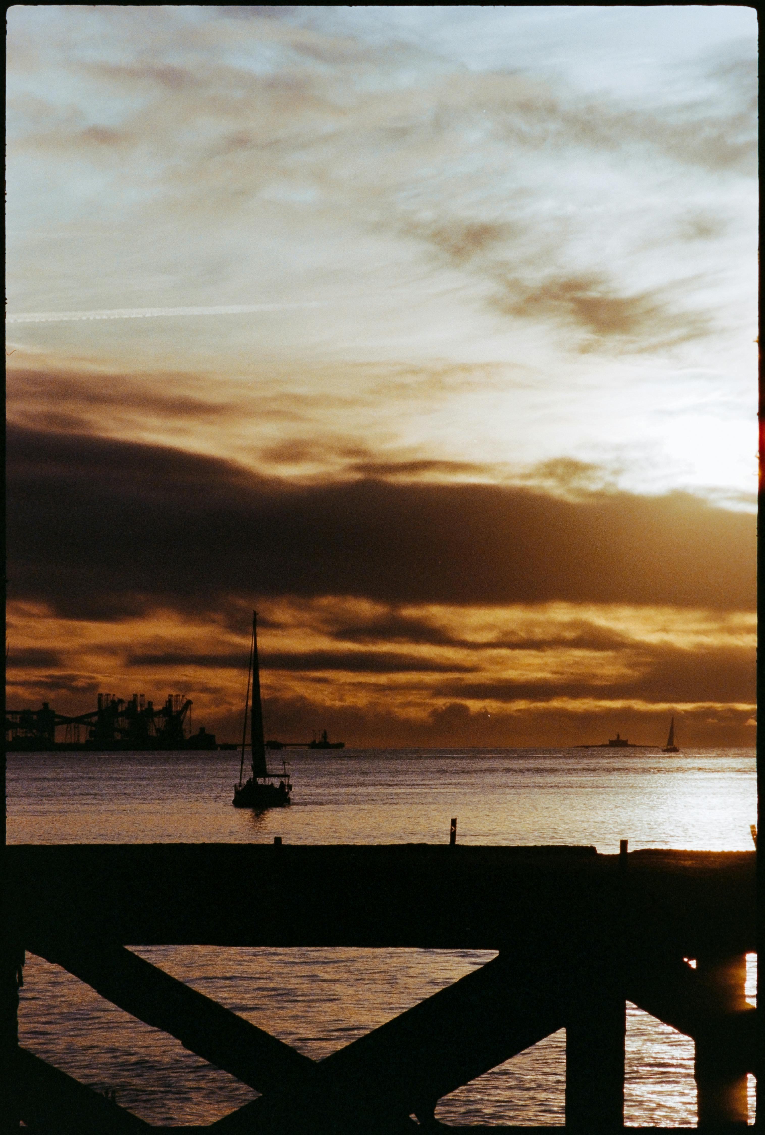 A tranquil scene of a sailboat silhouetted against a Lisbon sunset, highlighting calming waters and dramatic skies.