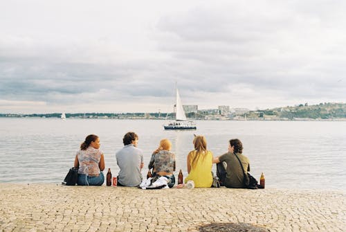 Four people sitting on a bench near the water