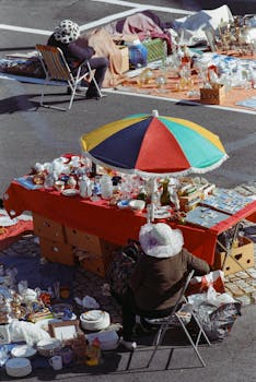 Flea market scene in Lisbon showcasing vibrant stalls and tradeswomen under a colorful umbrella.