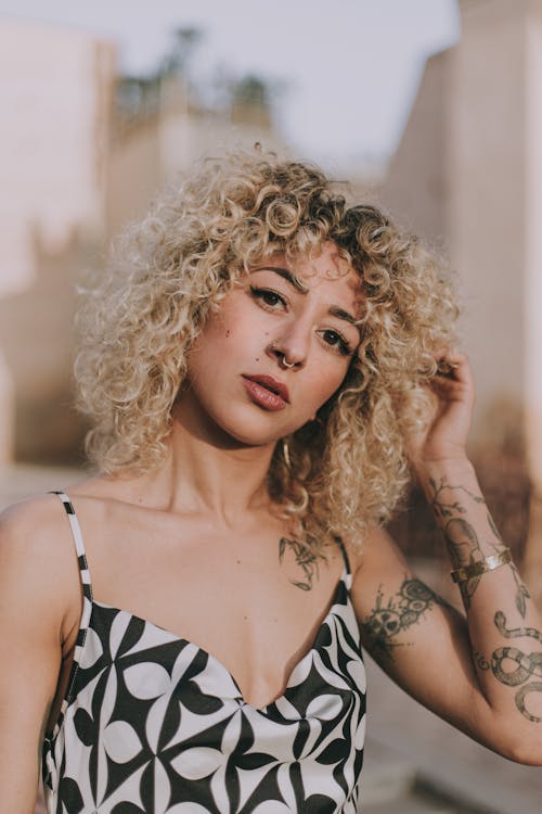 A woman with curly hair and tattoos
