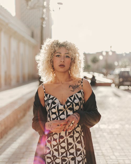 A woman with curly hair and a dress standing on a street