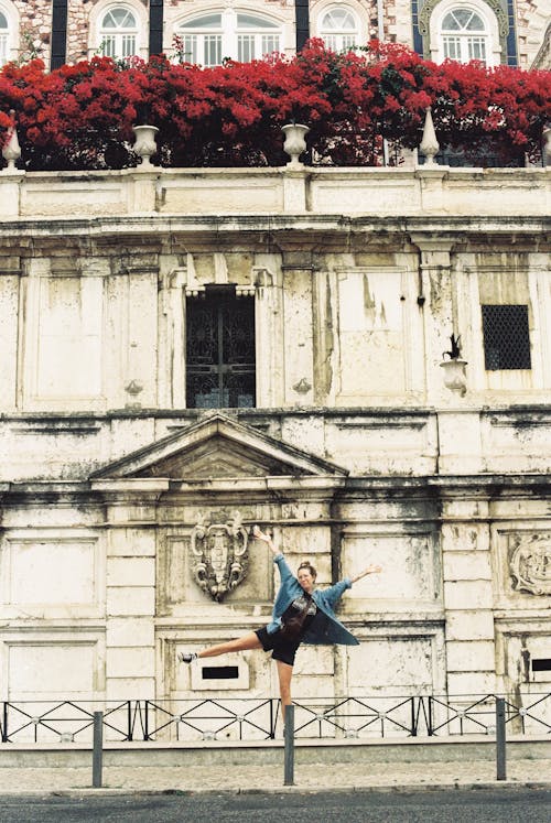 A woman is jumping in front of a building