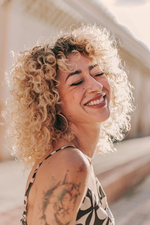 A woman with curly hair smiling and laughing