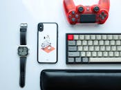 现代小工具的顶视图，包括智能手机、手表、游戏控制器和键盘