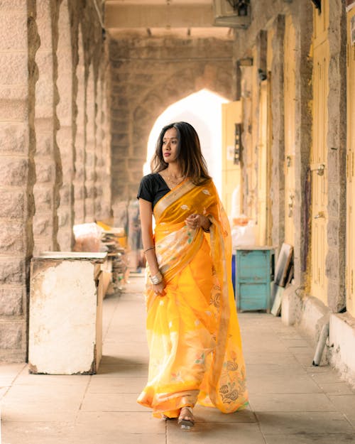 A woman in a yellow sari walking down a hallway