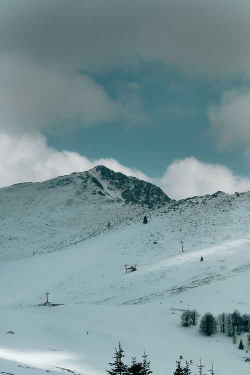 Free Aerial view of a snowy mountain with ski lifts, showcasing winter scenery. Stock Photo