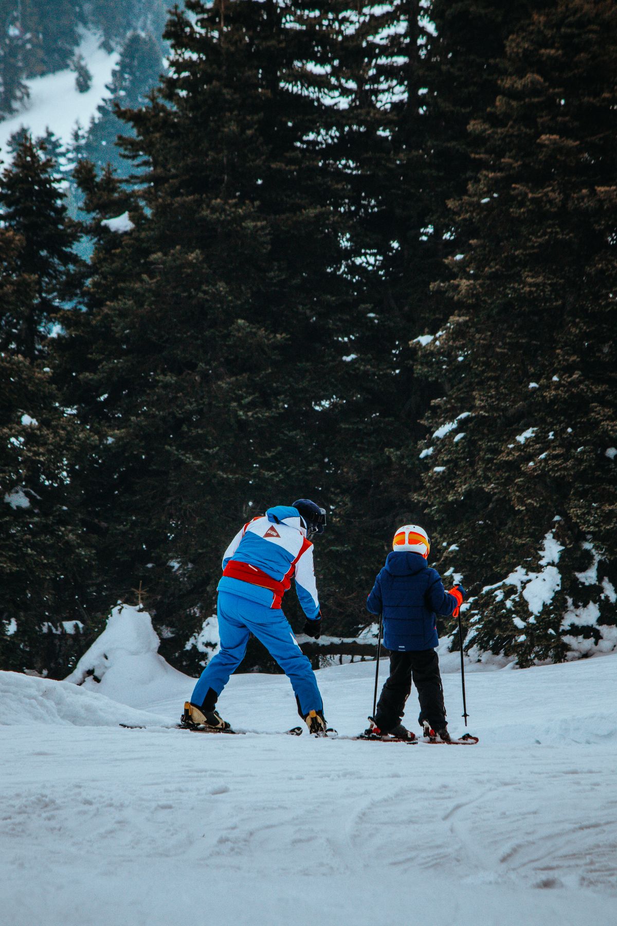 Kid skiing through trees with instructor