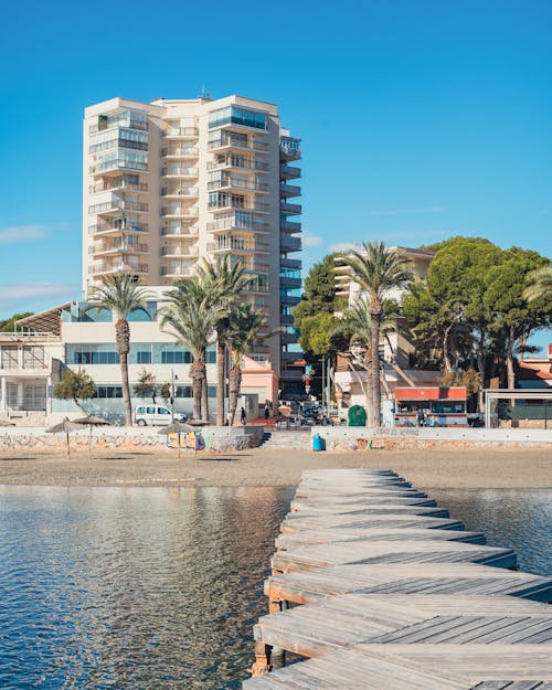 A wooden pier with a beach and buildings in the background