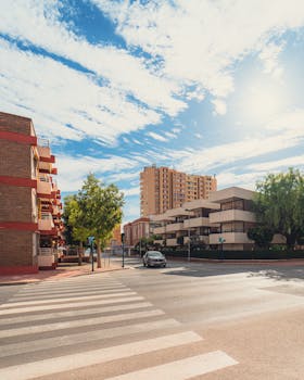 Bright city street view featuring residential buildings and a crosswalk under a sunny sky.