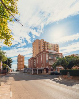 Sunny urban street with apartments and trees, perfect for real estate and city life themes.