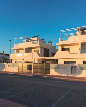Contemporary townhouses illuminated by sunset under clear skies on a quiet urban street.