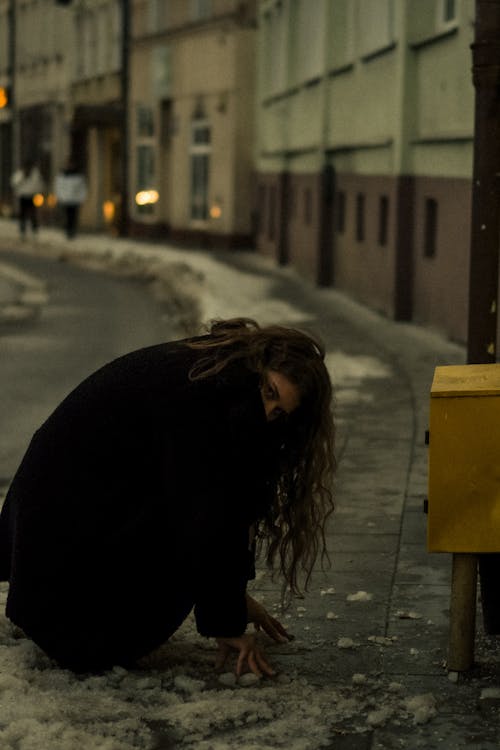 Woman Squatting on Street in Winter