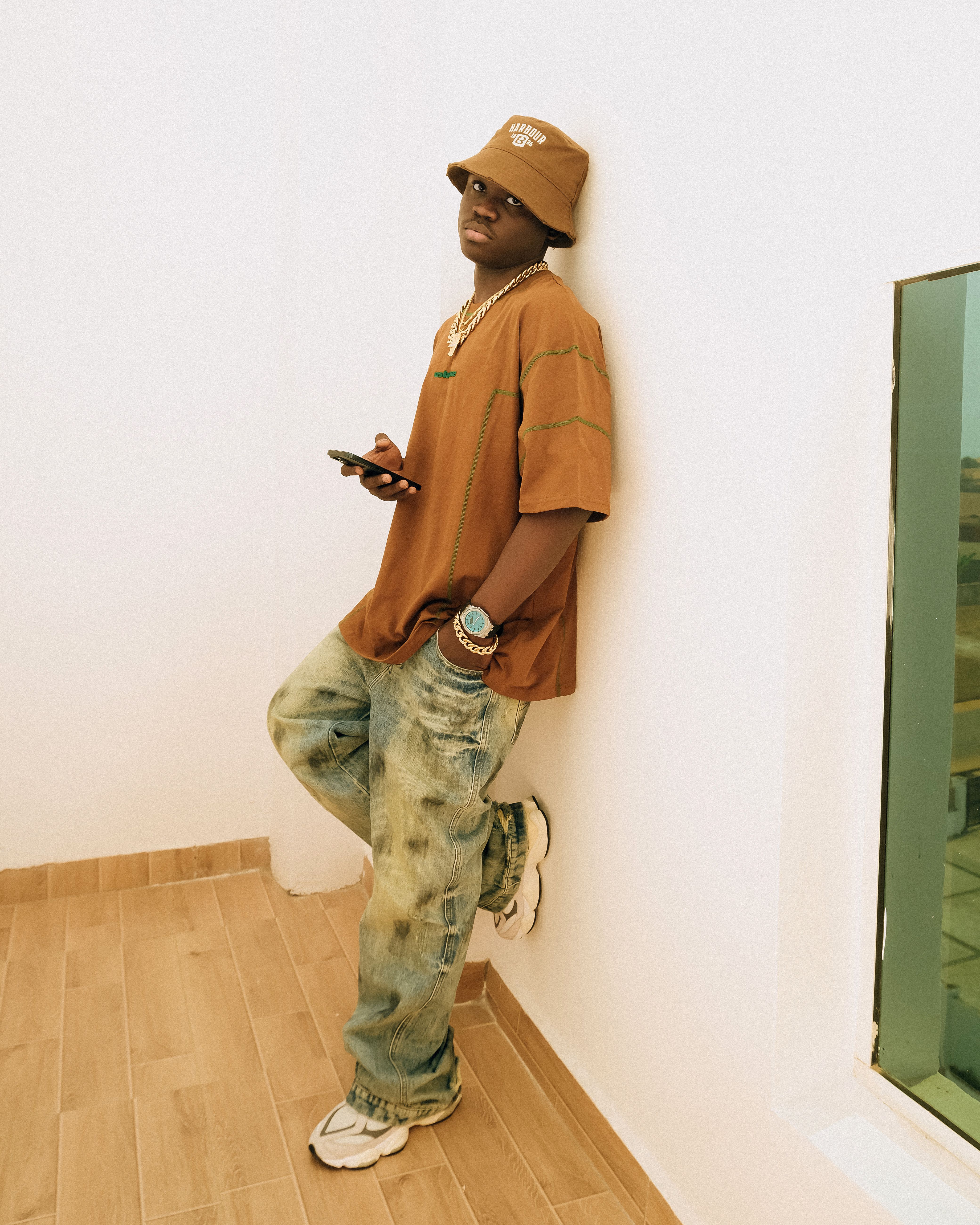 Young man in casual wear leaning against wall, exuding modern urban style.