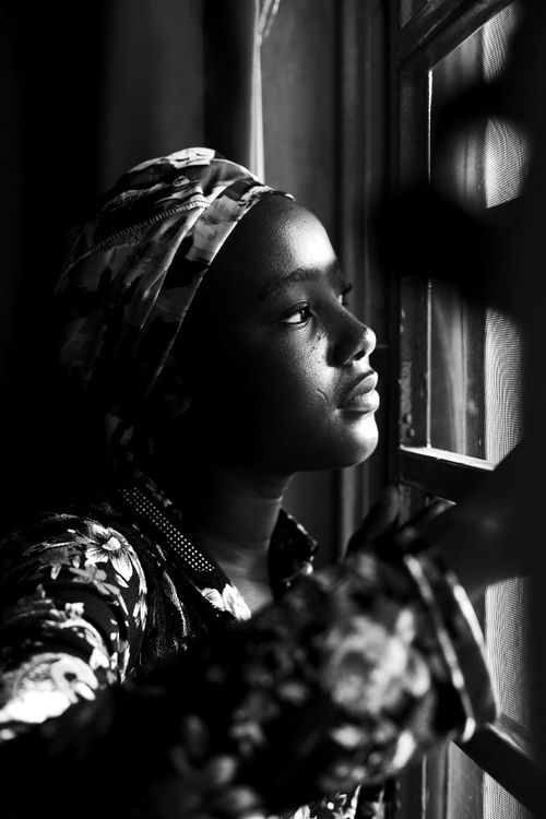 Free An artistic black and white portrait of a woman looking out the window, expressing a sense of contemplation. Stock Photo