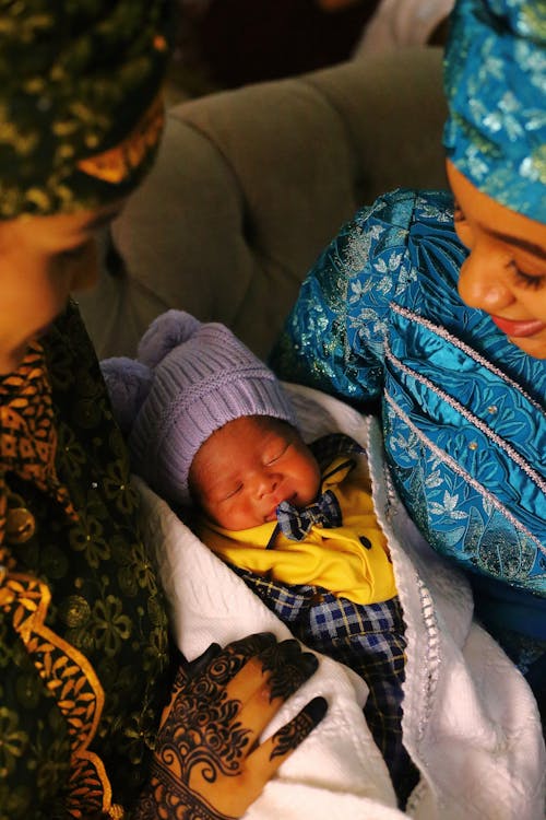 Women Sitting and Holding a Newborn Baby Wrapped in a Blanket 
