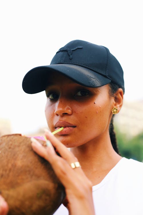 A woman in a baseball cap holding a coconut