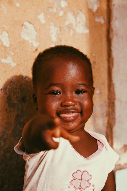 A smiling child pointing at the camera