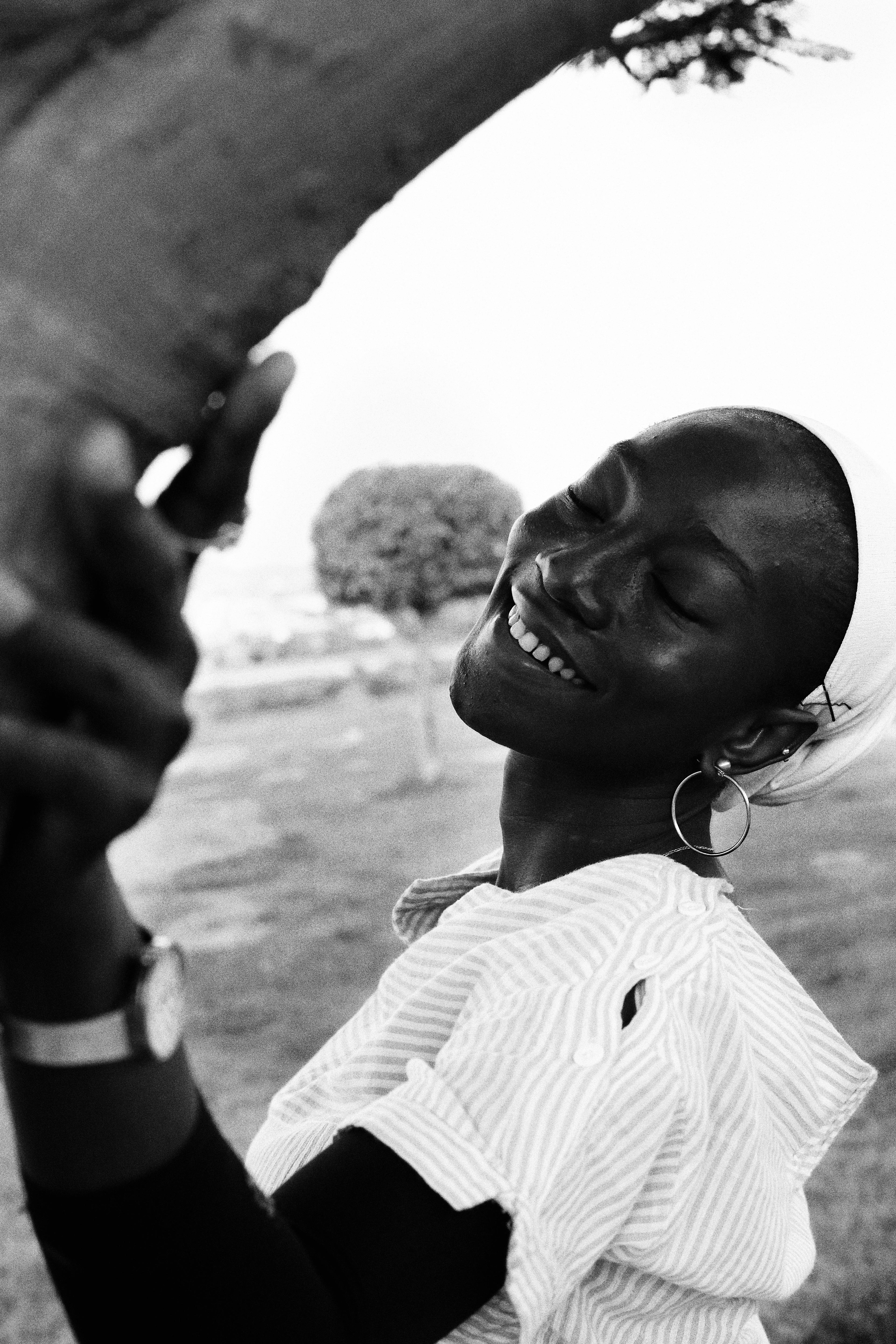 Elegant portrait of a smiling woman in black and white, exuding fashion and joy outdoors.