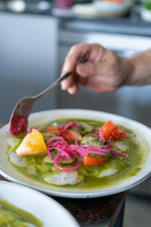 Free A colorful plate of fresh vegetables with a hand adding sauce for culinary presentation. Stock Photo