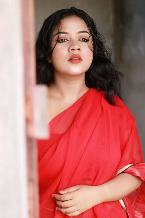 Anusha in red sari posing for the camera