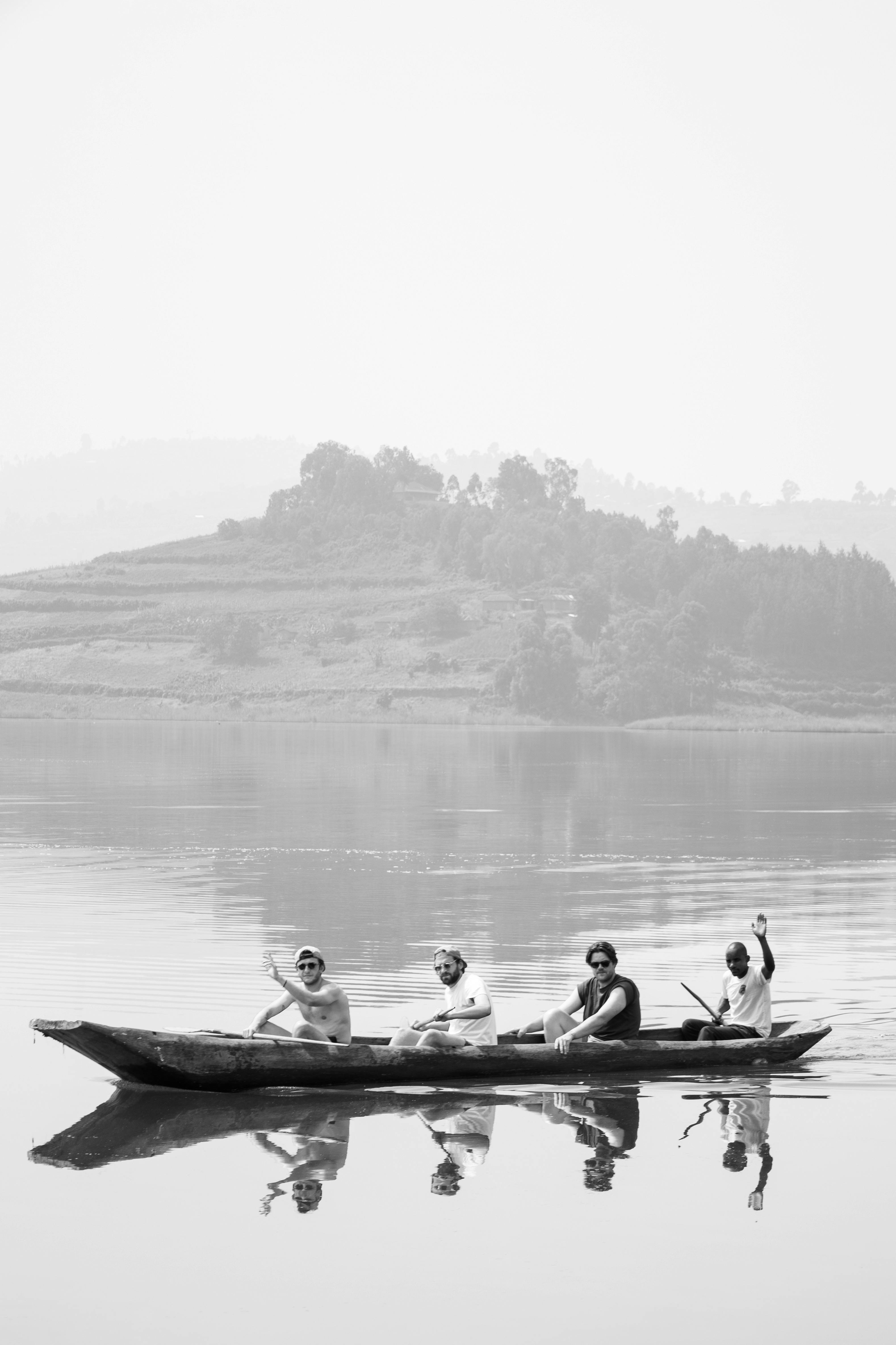 Four men paddling a canoe on a misty lake surrounded by hills.