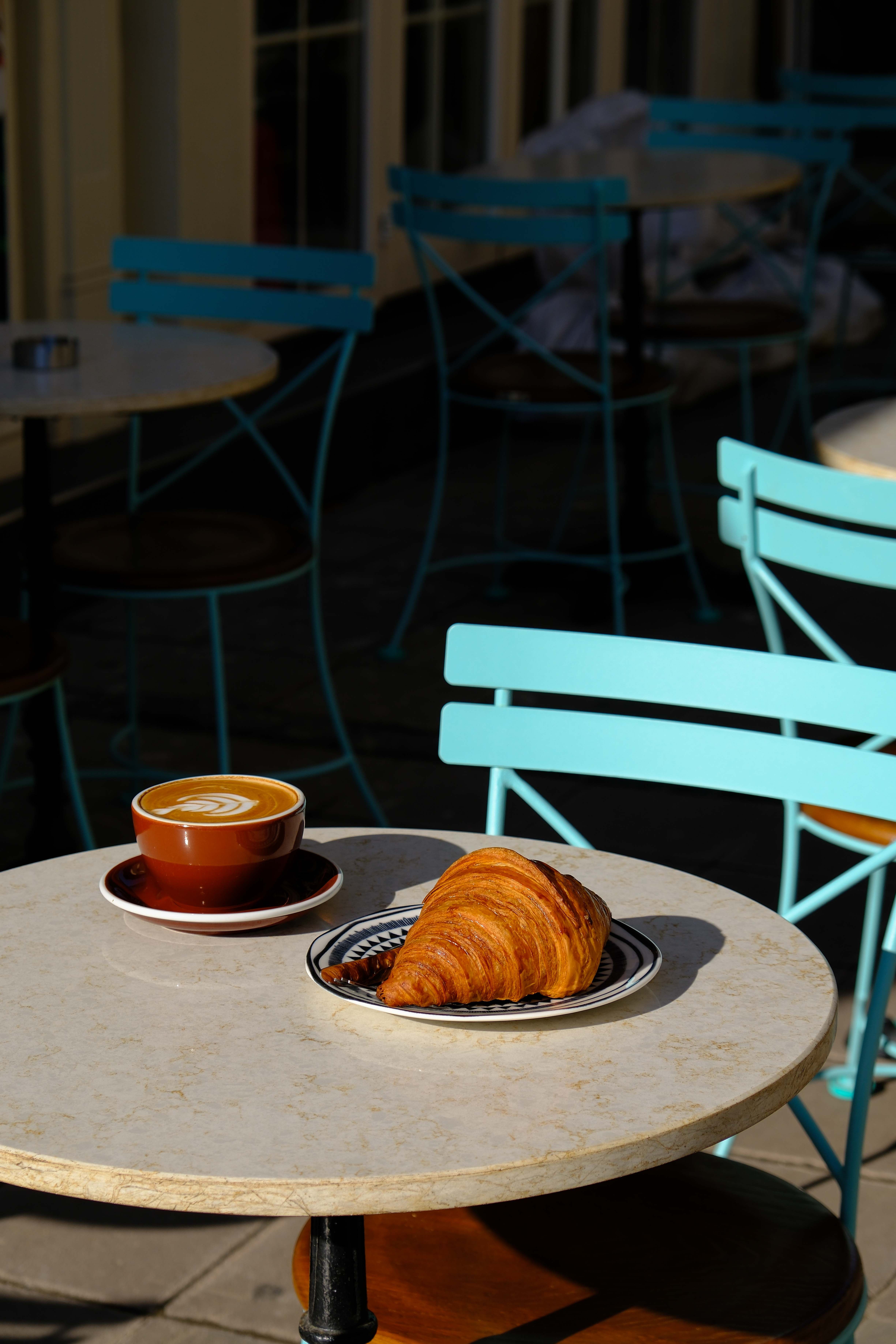 Garden table for two with a latte and croissant in the morning shade