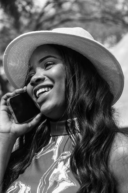 Young Woman Wearing a Fedora Talking on a Smartphone