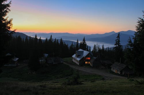 Пейзажная фотография дома в окружении сосен с видом на горный хребет