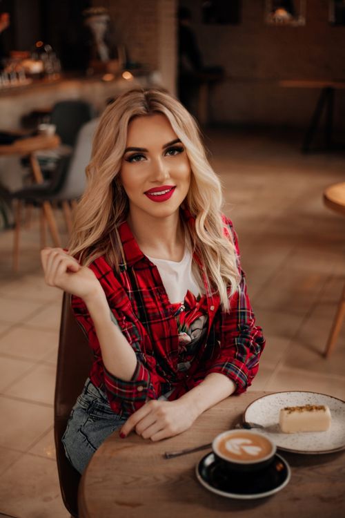 Free Stylish woman in a café with cake and coffee, wearing a red plaid shirt. Stock Photo