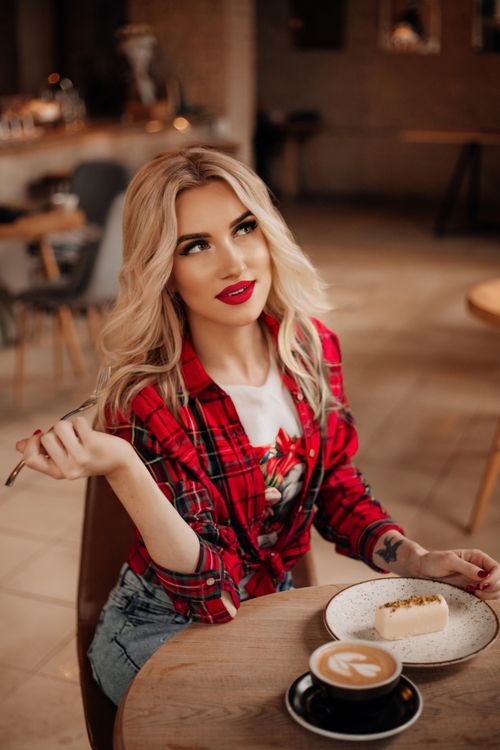 Free Stylish woman with coffee and pastry in a cozy café setting, relaxed atmosphere. Stock Photo