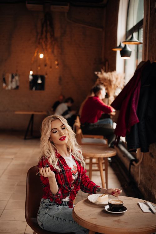 Free Blonde woman enjoying leisure time with coffee and pastry in a cozy café. Stock Photo